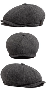 Detail of tweed newsboy cap showing grey plaid texture and side leather strap buckle