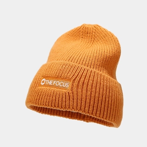 Detailed view of the thick knit texture and embroidered logo label on orange beanie