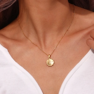 Detail of gold starburst compass pendant necklace worn on neck with elegant jewelry texture