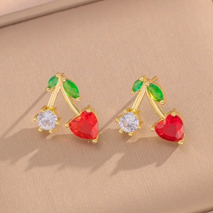 Elegant gold cherry earrings with red heart gems and green leaves on beige base
