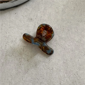 Handmade amber acetate hair claw clip with golden handwriting detail on grey background
