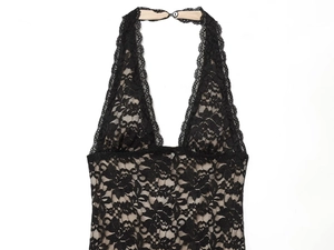 Detailed view of backless black lace halter dress with beige lining and intricate floral patterns