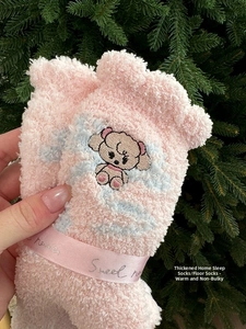 Close-up of pink coral fleece socks with cute bear embroidery and satin ribbon detail