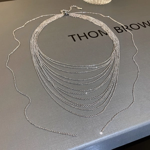 Close-up of a silver multi-layer layered chain necklace with detailed metal textures