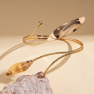 Macro detail of golden leaf arm cuff bracelet with metallic texture on natural stone