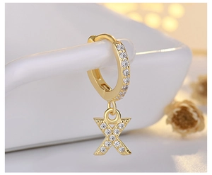 Macro view of gold hoop earring with letter X pendant and sparkling pave zirconias