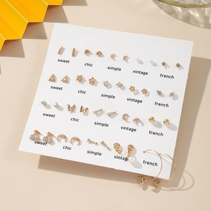 Detailed set of golden heart and pearl earrings displayed on a white branded card