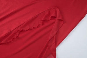 Détail de robe rouge tricotée montrant les bords ondulés et la fente latérale
