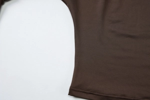 Détail de la texture en maille fine et de l'ourlet à double couture sur un haut marron