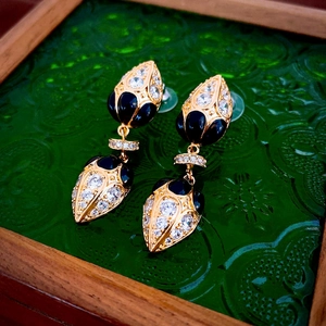 Detailed close-up of vintage gold-plated earrings with black teardrop gems and white zircons