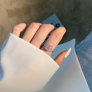 Macro view of a luxurious pink rectangular diamond ring with stepped side stones on finger