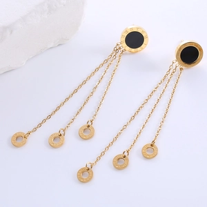 Detailed view of gold tassel earrings featuring Roman numeral discs and metal chains