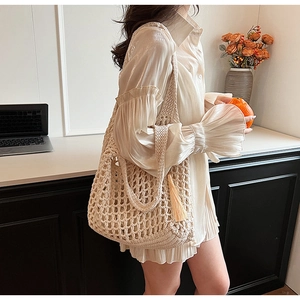 Detail of beige knit tote bag with tassel fringe and hollow weave pattern for women