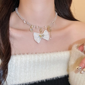 Detail of fabric bow necklace with pearls and celestial charms on a female model