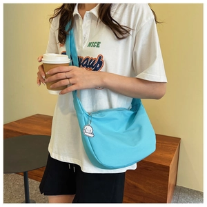 Close-up of light blue nylon dumpling bag with cute white puppy pendant and zipper