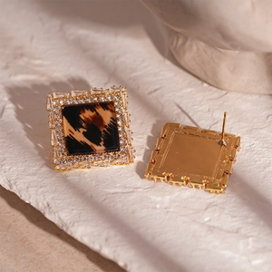Close-up of golden square leopard print earrings with sparkling zircon borders