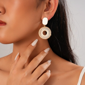 Golden woven circle earrings with white oval studs on professional female model