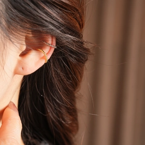 Detail of gold and silver beaded ear cuffs worn as a stack on a female model's ear