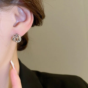 Close-up of minimalist silver twisted knot earrings worn for a sleek fashion statement