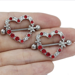 Close-up of heart-shaped nipple rings with red and white zircons in a silver metal base
