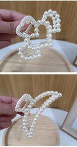 Detail of elegant hair claws with heart shape and large faux pearls on wood