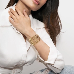 Close-up of minimalist layered golden wire-wrapped cuff bracelet on model's wrist