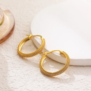 Macro detail of 18K gold-plated hoop earrings with micro-paved sparkling cubic zirconia