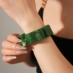 Detail of green acrylic resin bangle with vertical wave texture and marbled pattern