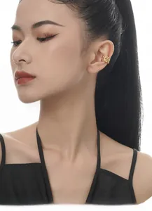 Detailed view of a gold hollow lattice ear cuff worn on the ear cartilage