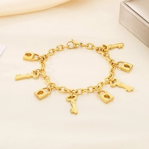 Macro shot of 18K gold plated lock and key charms on a stylish stainless steel bracelet