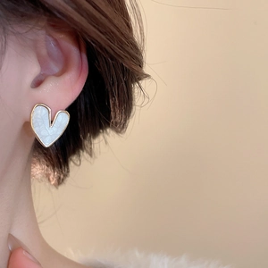 Close-up of heart stud earring featuring white marble texture and gold metal frame