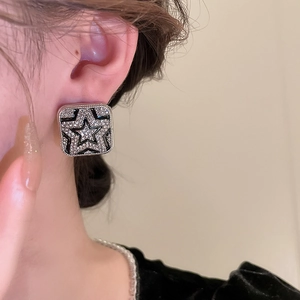 Detailed view of luxury square star earrings with black enamel and sparkling zircons