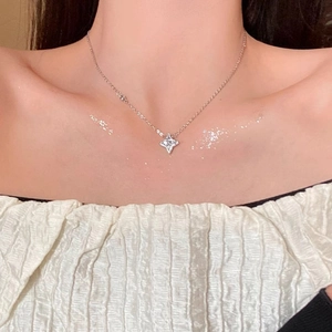 Close-up of sparkling four-pointed star pendant necklace on model's collarbone