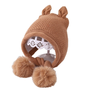 Cute winter knit baby hat with bear ears and fluffy pom-poms in warm khaki brown color