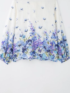 Detail of floral print blouse showing blue and purple flower patterns on white chiffon fabric