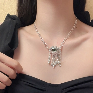 Silver evil eye necklace with green bead and pearl tassels shown on model's neck