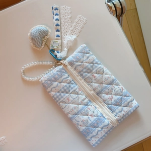 Macro shot of blue floral quilted fabric with pearl strap and heart pendant detail