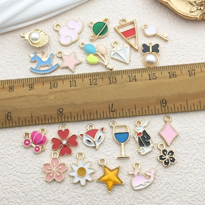 Detail of colorful enamel charms and pendants with ruler showing sizes 1cm to 2.5cm