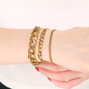 Detailed close-up of three layered golden titanium steel NK chain bracelets on a wrist