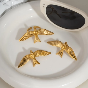 Trois bagues hirondelles dorées au design ouvert dans un plat en céramique