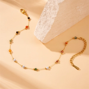 Ethnic style gold plated stainless steel anklet with colorful beads on a beige stone