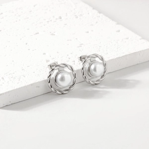 Elegant twisted silver stainless steel stud earrings with round white pearls on marble