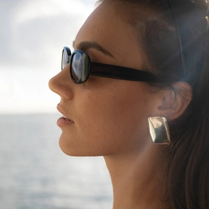 Minimalist square hammered silver titanium steel earrings worn by a model at the beach