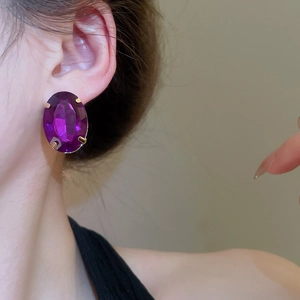Close-up of a large oval purple gemstone earring in a vintage gold-toned setting
