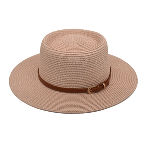 Detail eines beigen Strohhutes mit braunem Lederband und eleganter goldener Schnalle
