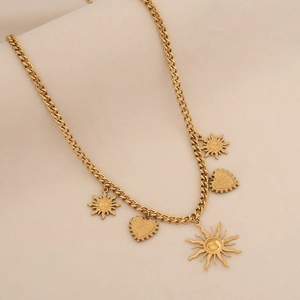 Dettaglio della collana a maglia groumette dorata con ciondoli a sole e a cuore