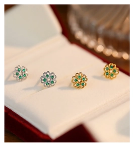 Macro shot of French style floral stud earrings with green gemstones in hollow silver settings
