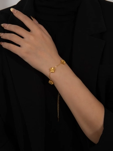 Macro detail of gold five-petal flower bracelet with radial brushed texture on wrist