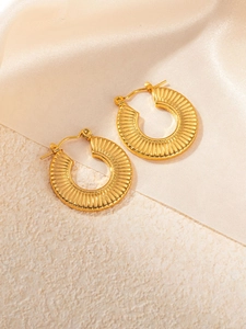 Macro detail of golden irregular water ripple earrings on elegant silk background