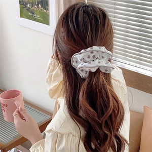Detail shot of a floral fabric scrunchie in cream and lavender on a ponytail